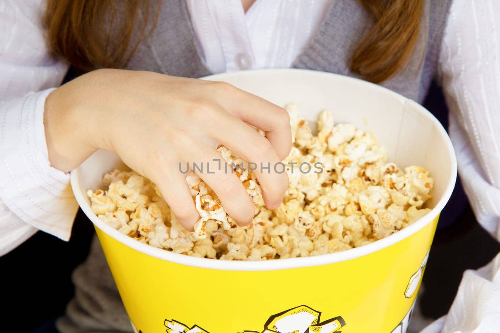 child's hand in a bucket of popcorn