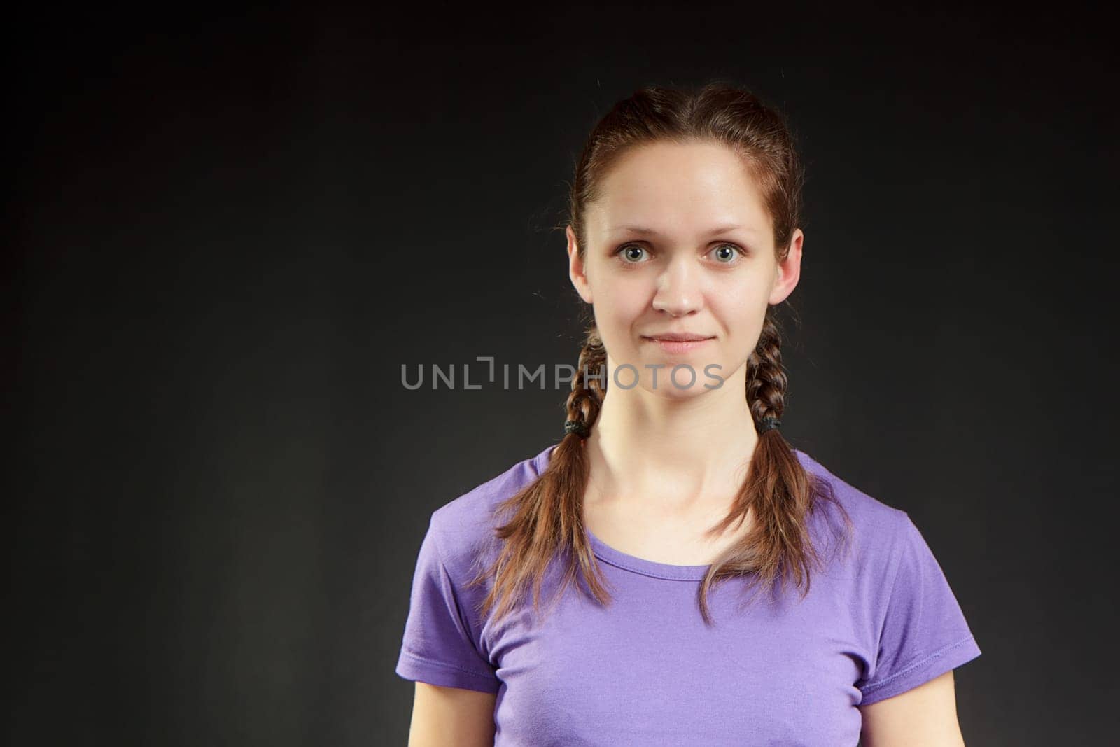 cute girl with pigtails in a T-shirt on a dark background