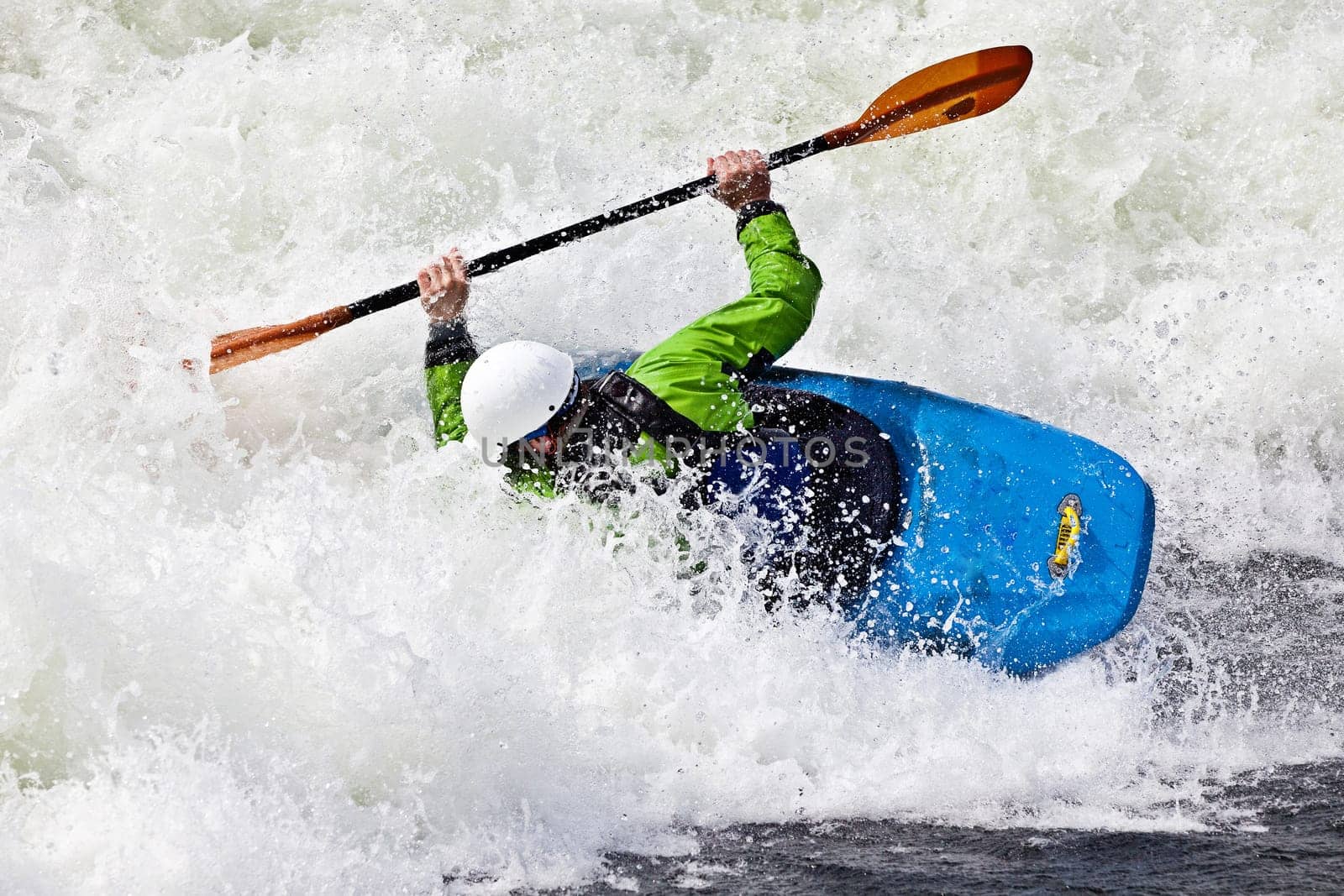 an active male kayaker rolling and surfing in rough water