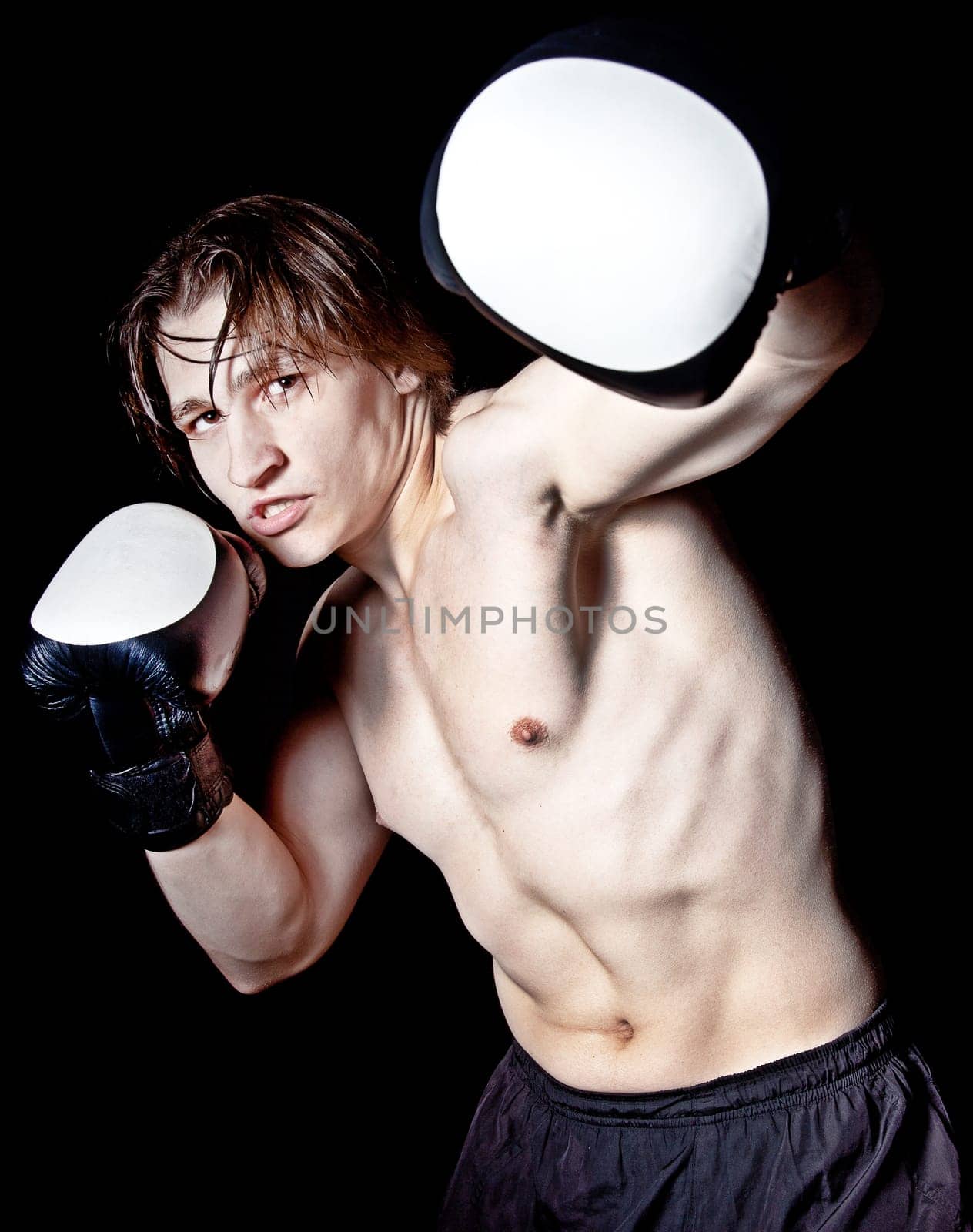 Young caucasian man boxing with gloves on black background