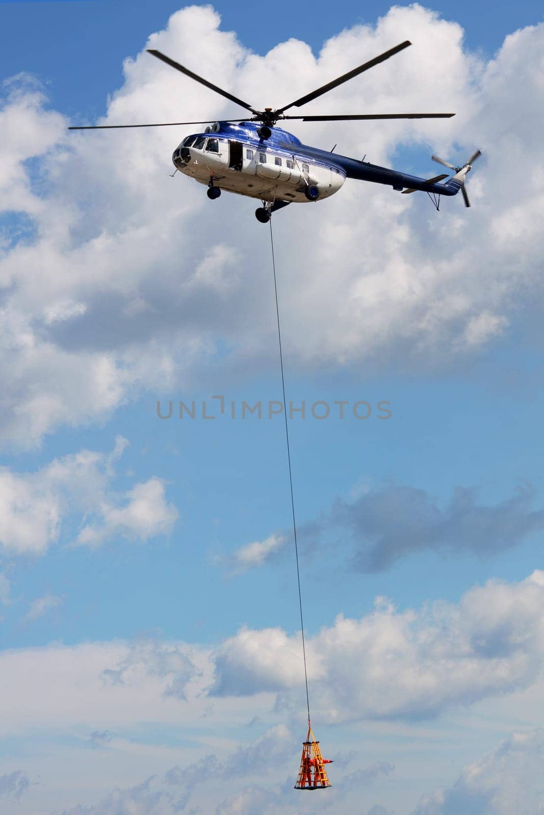 Helicopter with two people hanging, flying in a rescue mission