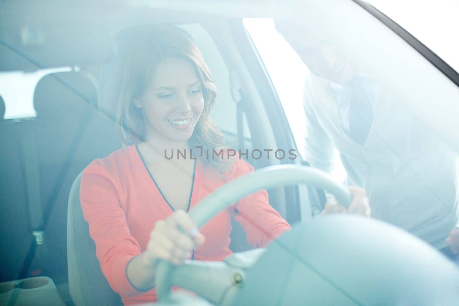 Photo of smiling woman sitting in car with salesman near by