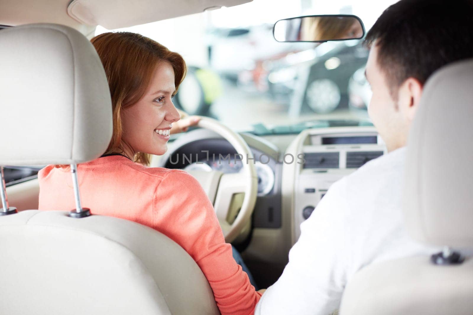 Rear view of pretty woman sitting in car and looking at salesman
