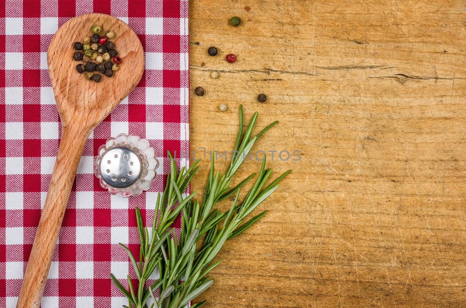Rustic wooden background with checkered tablecloth and cooking spoon