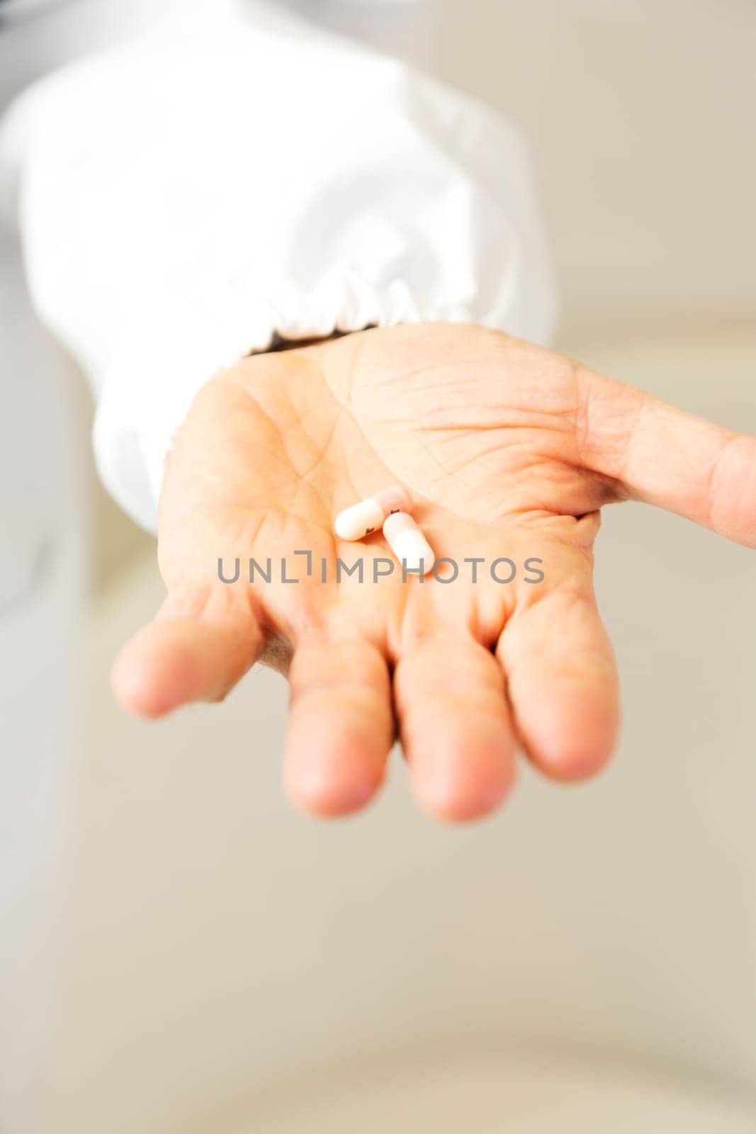 Doctor holding white and pink pills against anxiety on light gray background