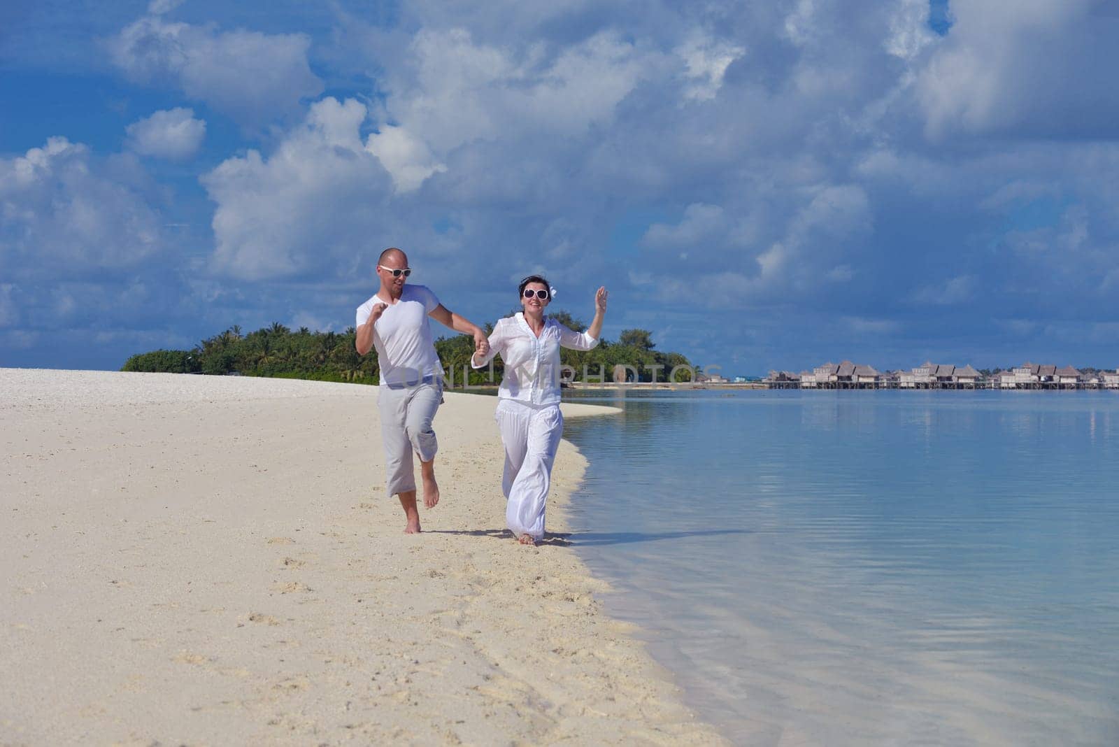 happy young couple have fun and relax at summer vacation on background maldives travel location and beautiful white sand beach