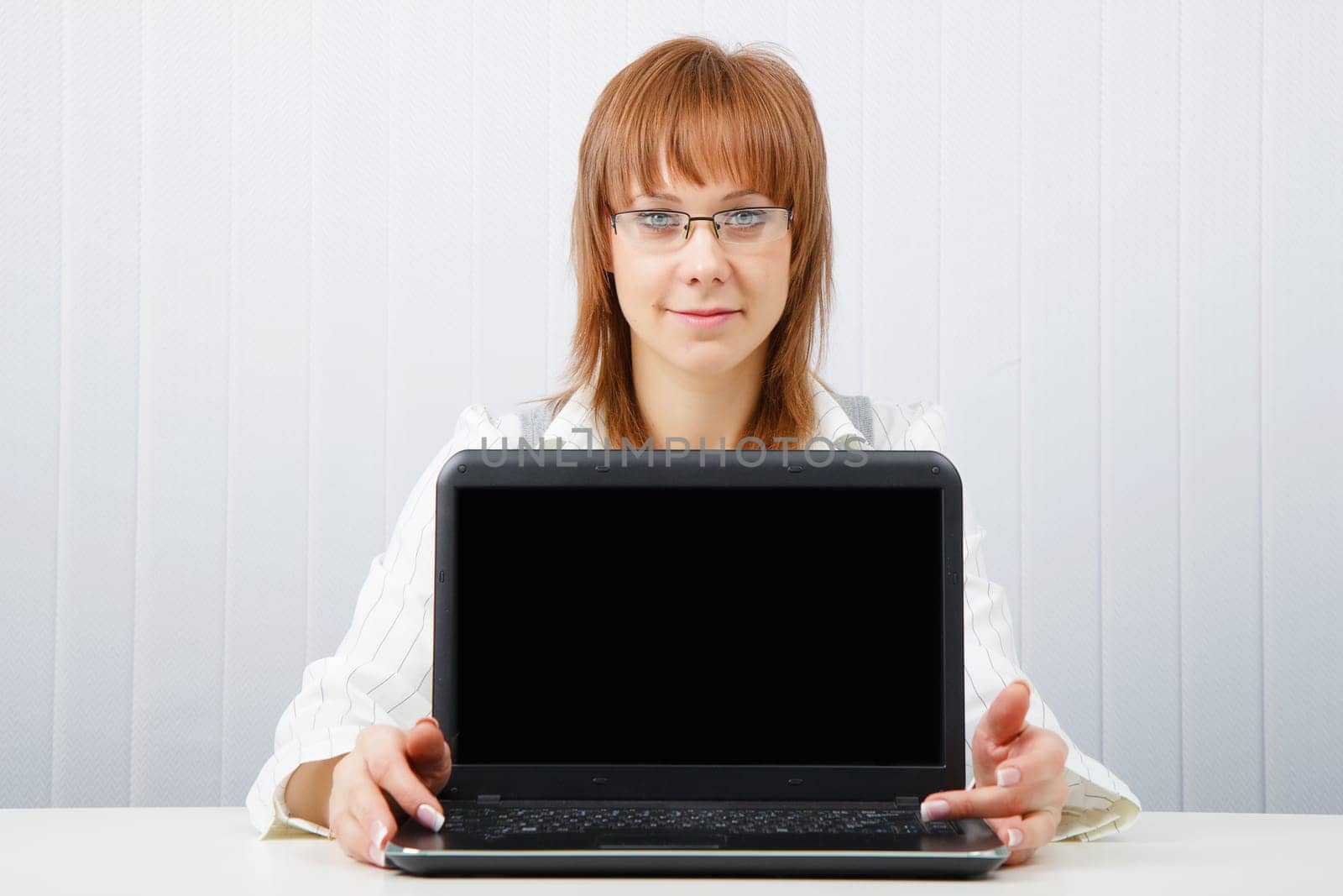 Attractive girl in glasses with a laptop in the office