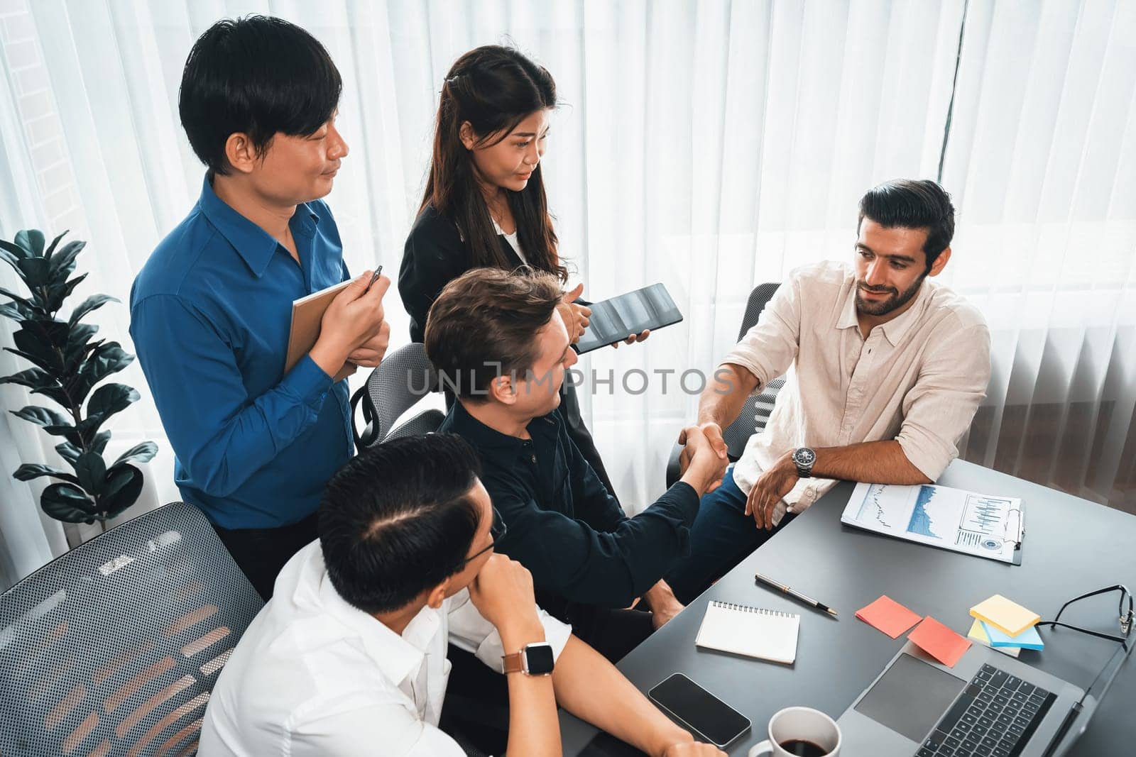 Diverse group of office employee worker shake hand after making agreement on strategic business marketing meeting. Teamwork and positive attitude create productive and supportive workplace. Prudent