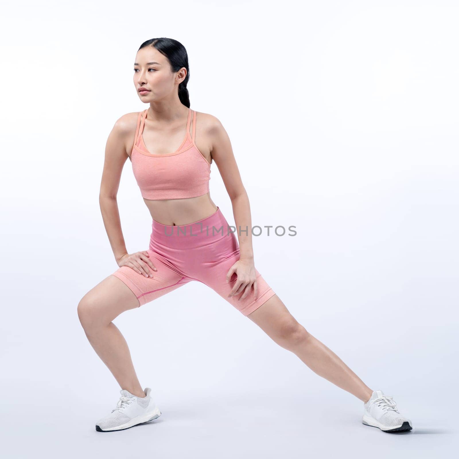 Young attractive asian woman in sportswear stretching. Vigorous by biancoblue