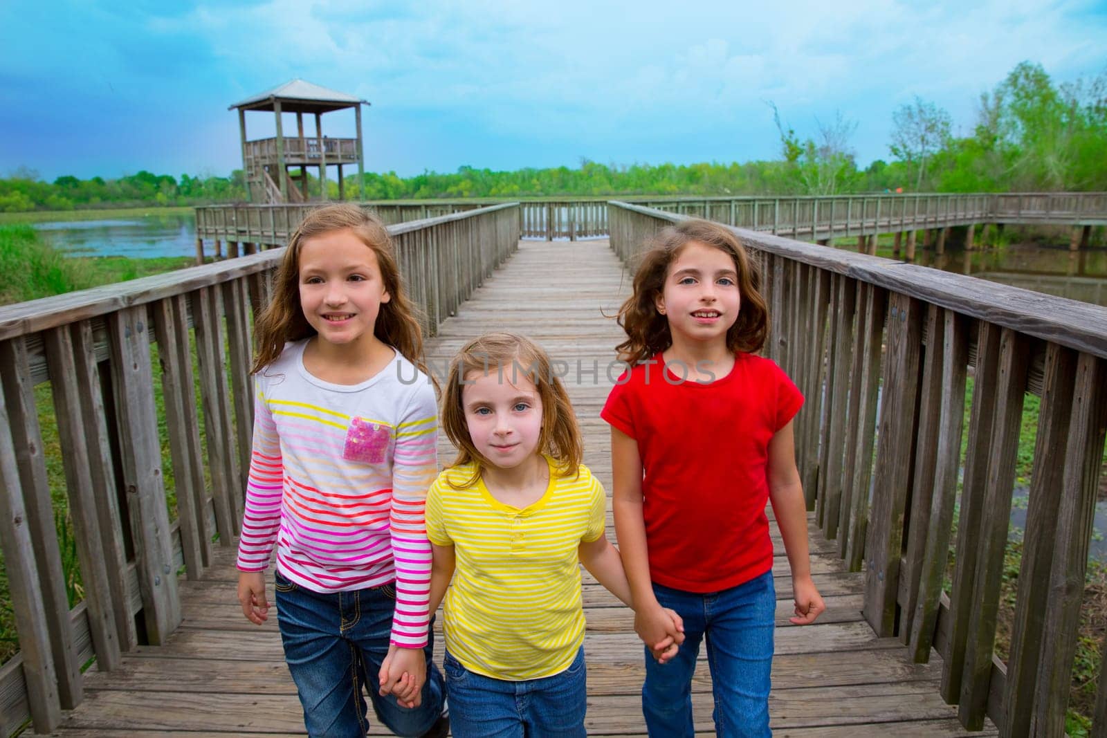 sister friends walking holding hands on lake wood smiling