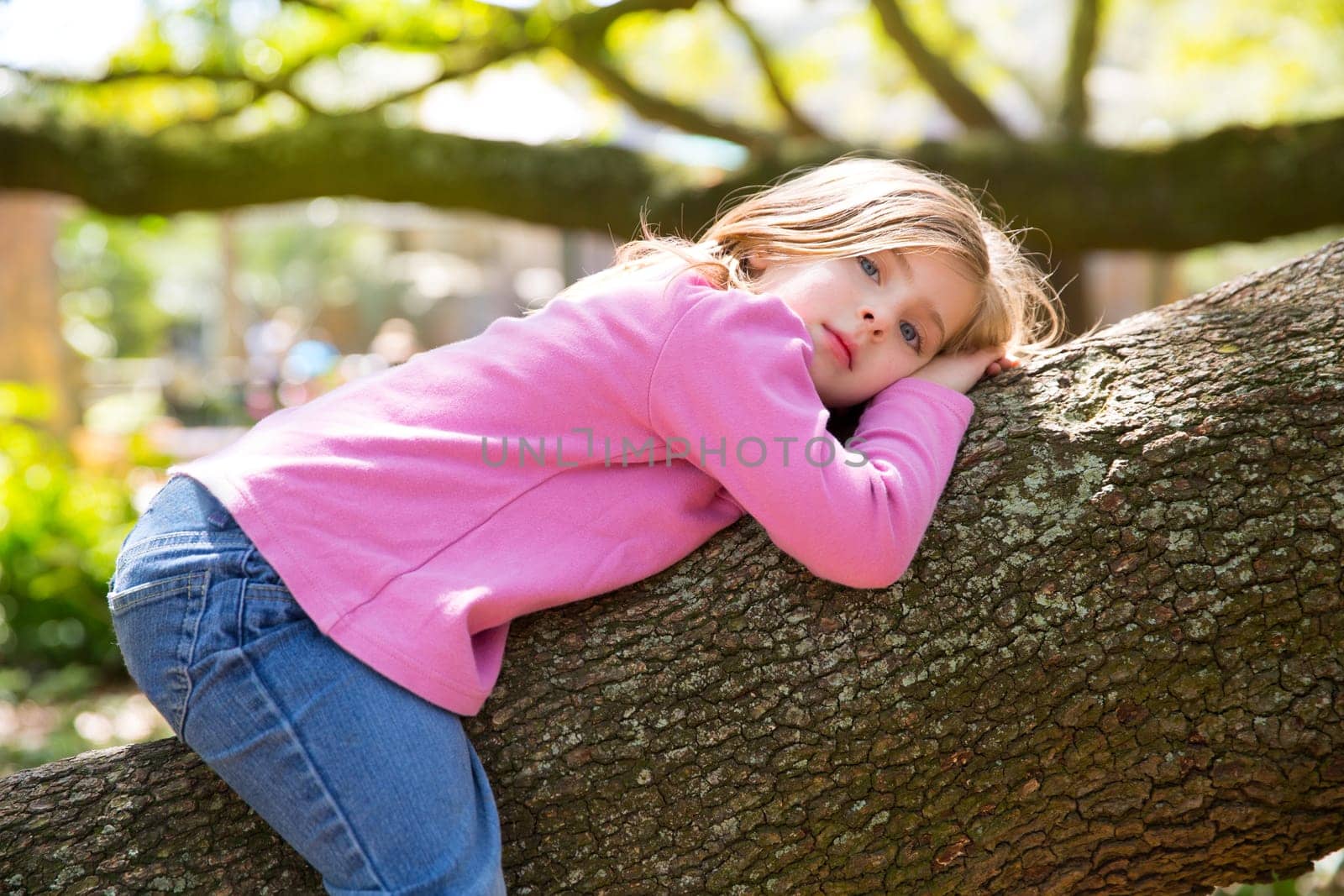 Beautiful children kid girl resting lying on a tree branch