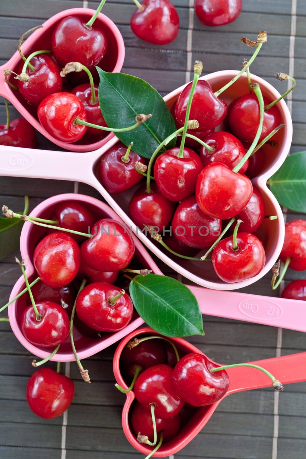 Fresh cherries in heart-shaped measuring cups