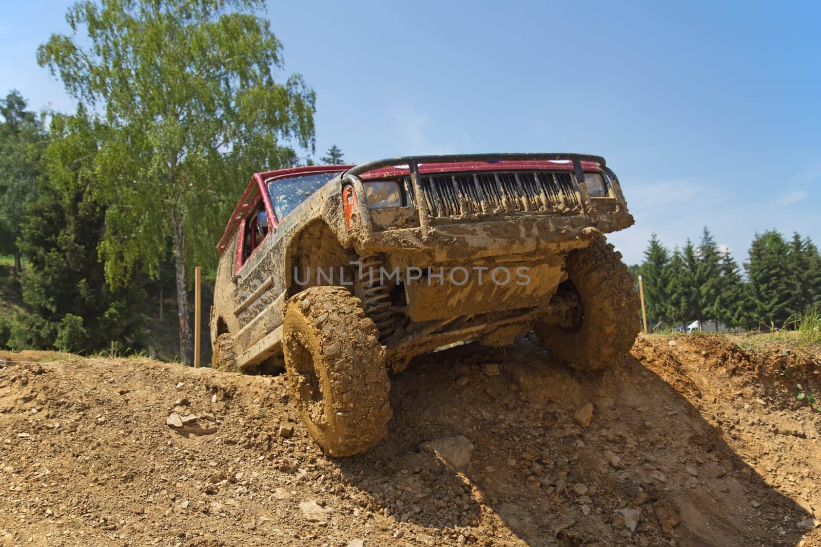 Red SUV overcomes steep muddy slope. All potential trademarks are removed.
