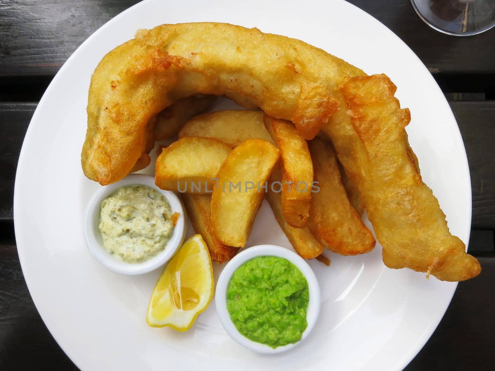 Fish and chips served with french fries, mushy peas and tartar sauce
