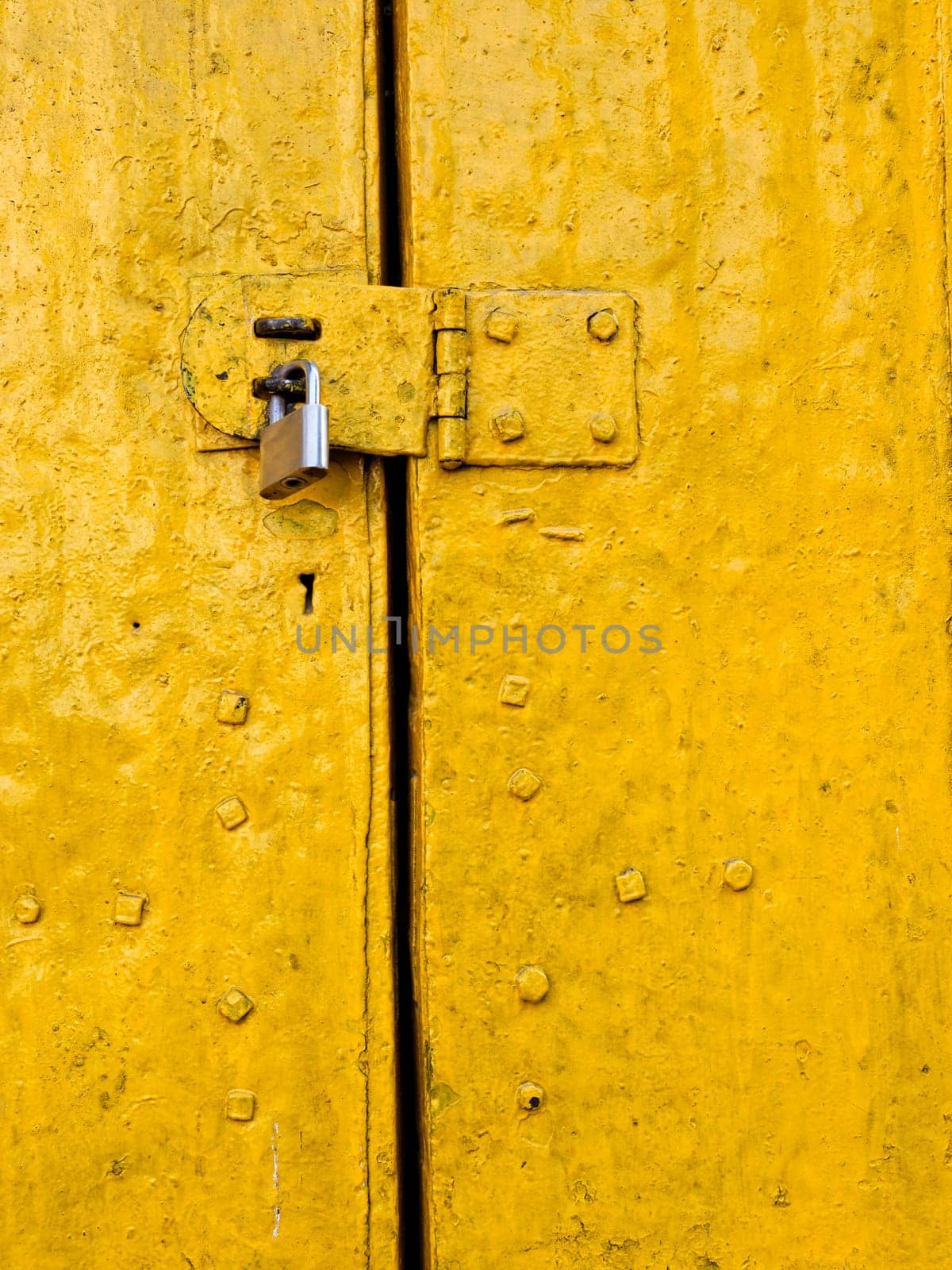 Padlock on an old yellow metallic door