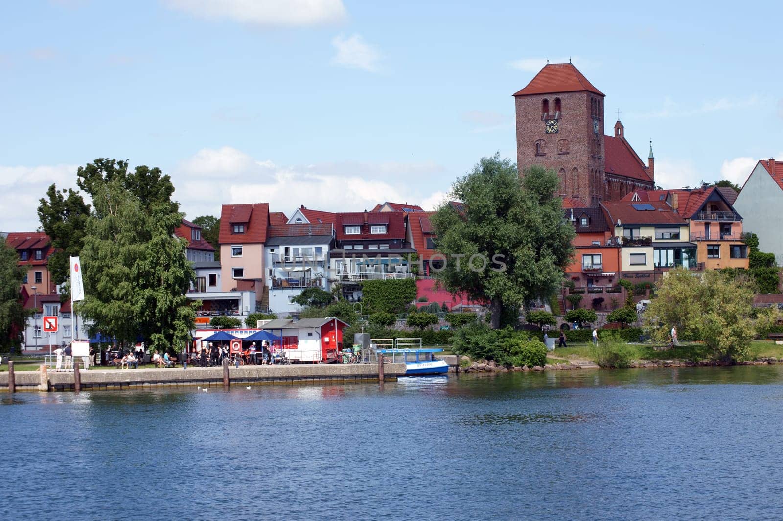 Waren,Mecklenburg Vorpommern/Germany – June 09,2013: People sit in a snack bar and walk along the promenade of Lake Mueritz on June 9th in Waren.