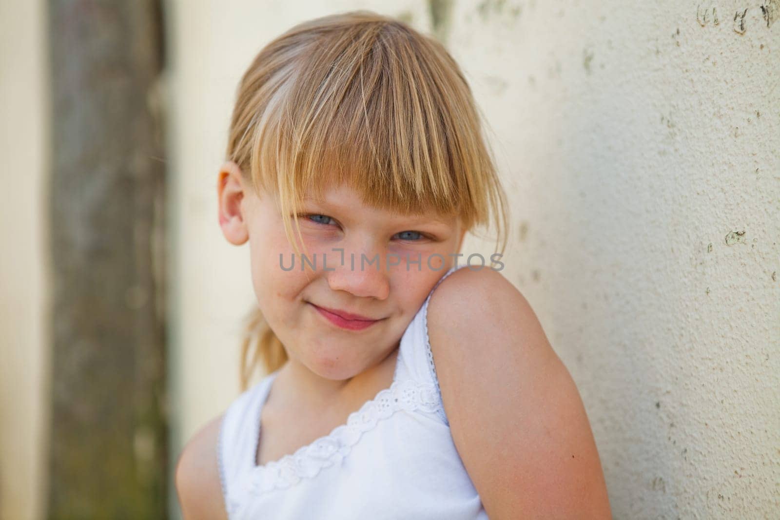 Portrait of cute smiling young girl in front of concrete wall outside