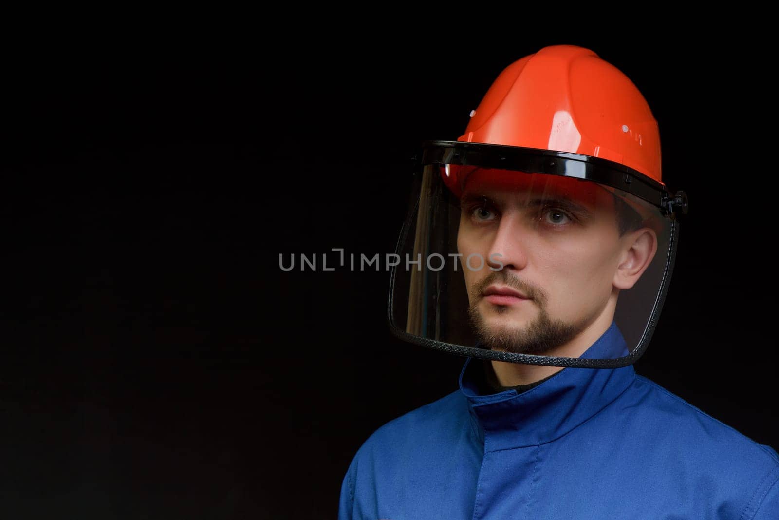 The worker in overalls and a helmet on a black background