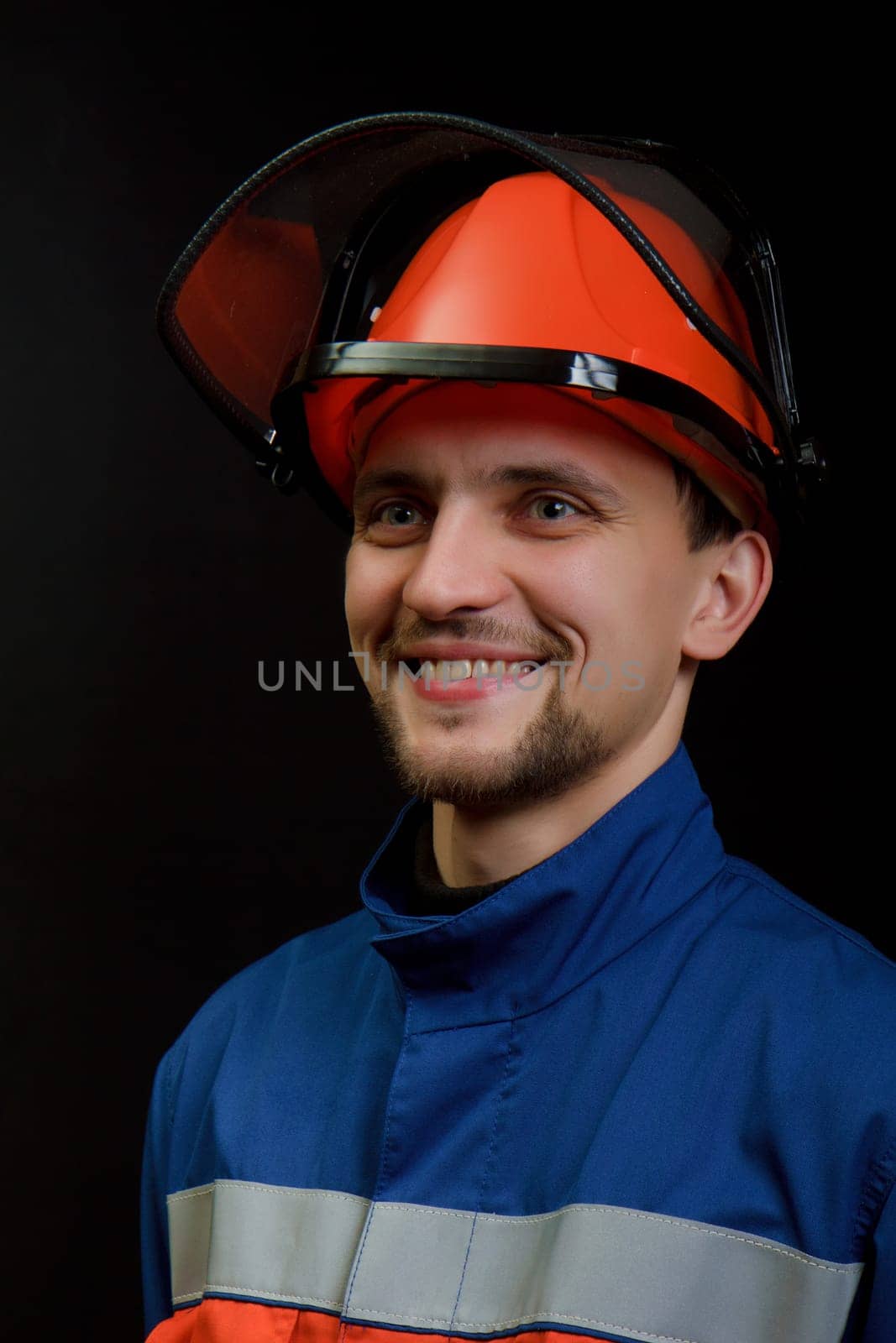 The worker in overalls and a helmet on a black background