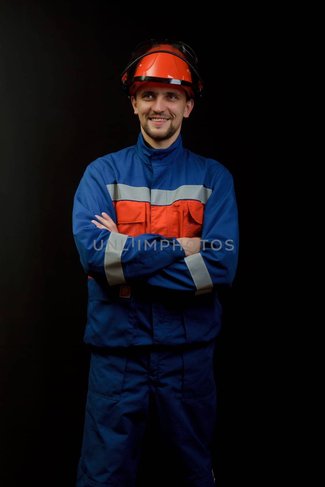 The worker in overalls and a helmet on a black background