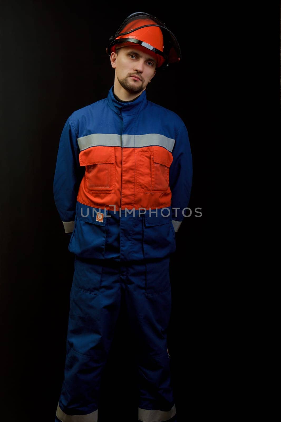 The worker in overalls and a helmet on a black background