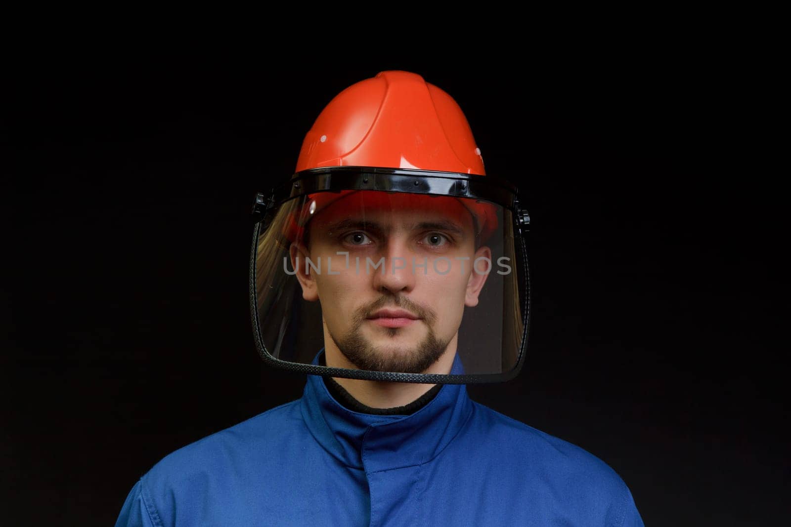 The worker in overalls and a helmet on a black background