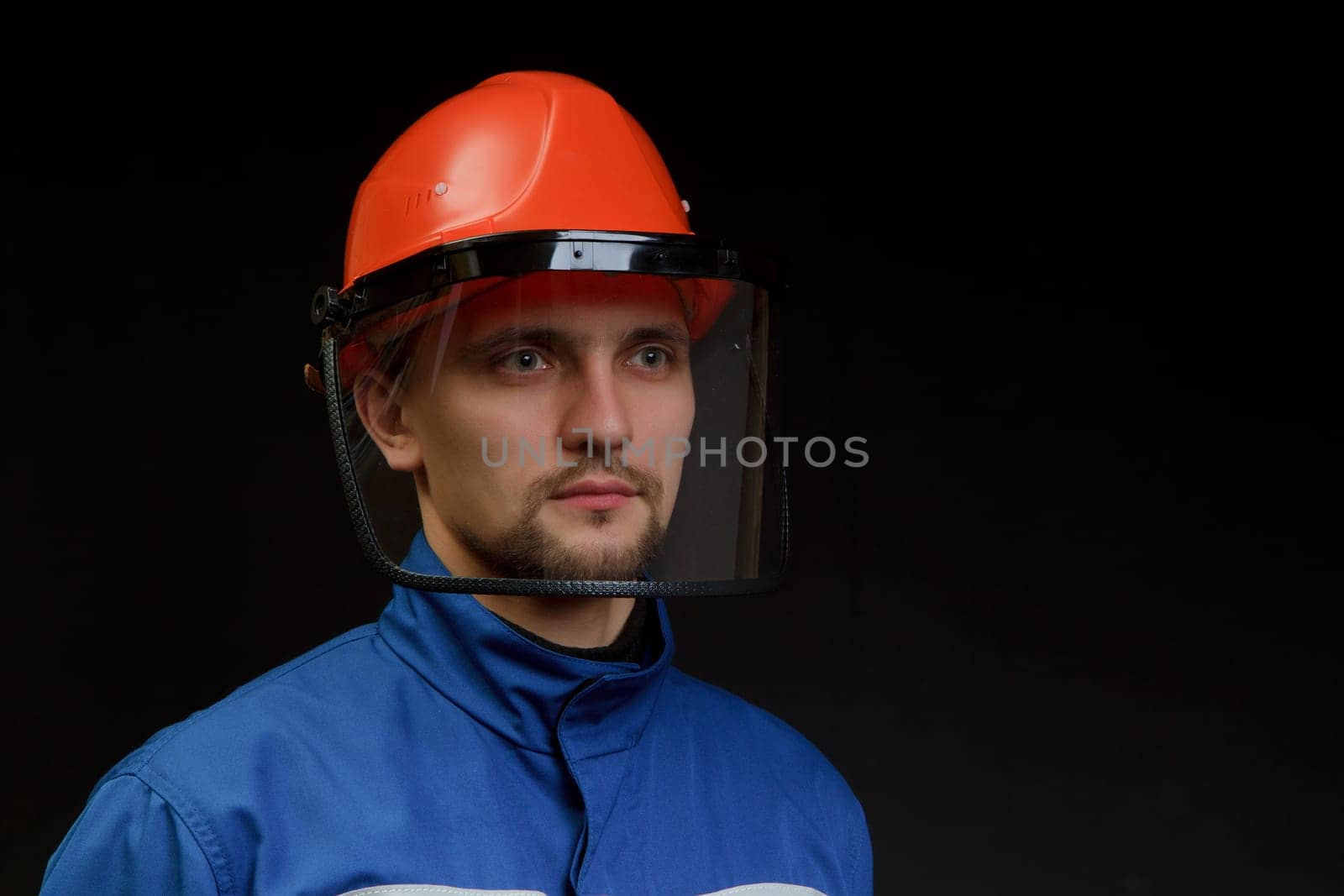 The worker in overalls and a helmet on a black background