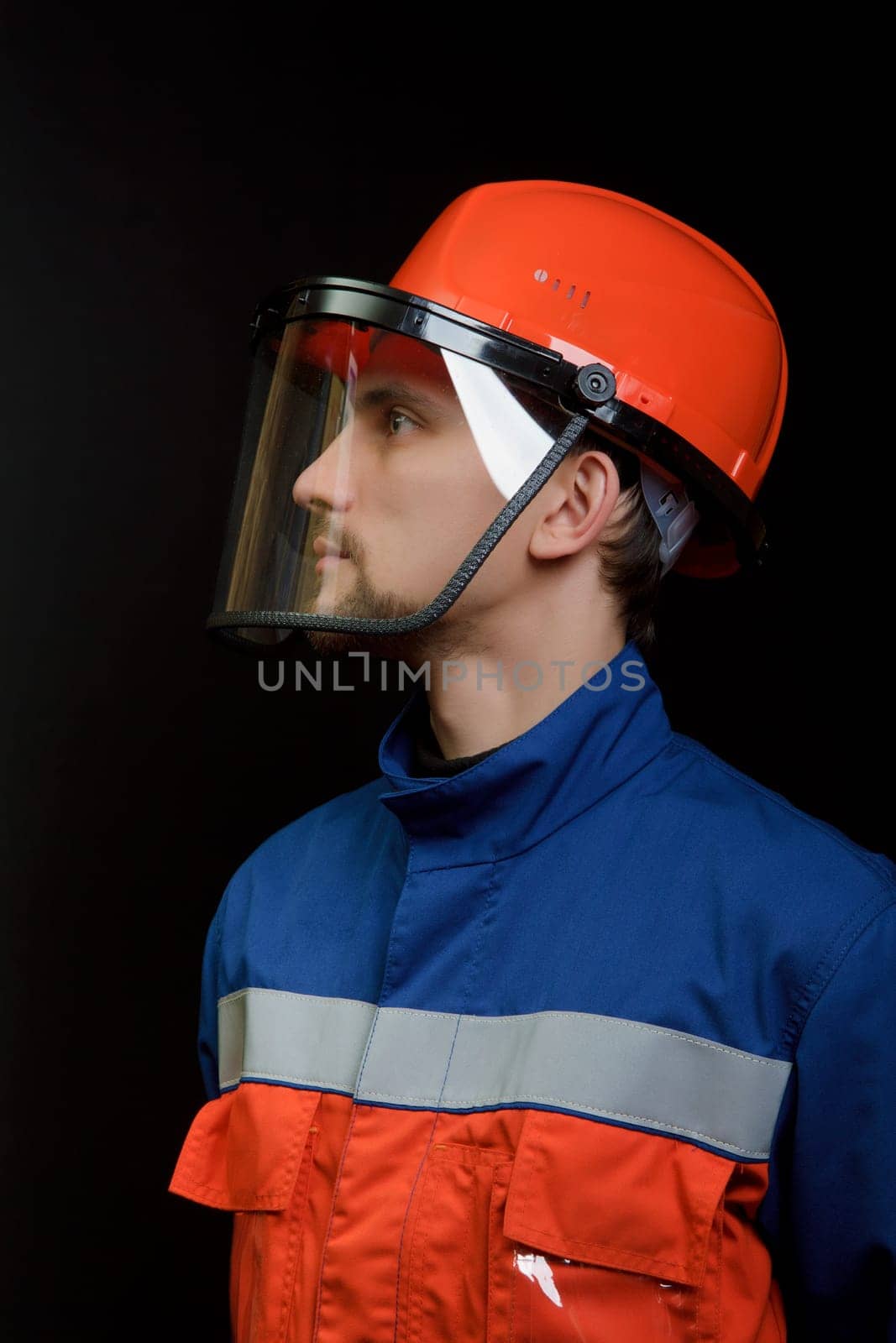 The worker in overalls and a helmet on a black background