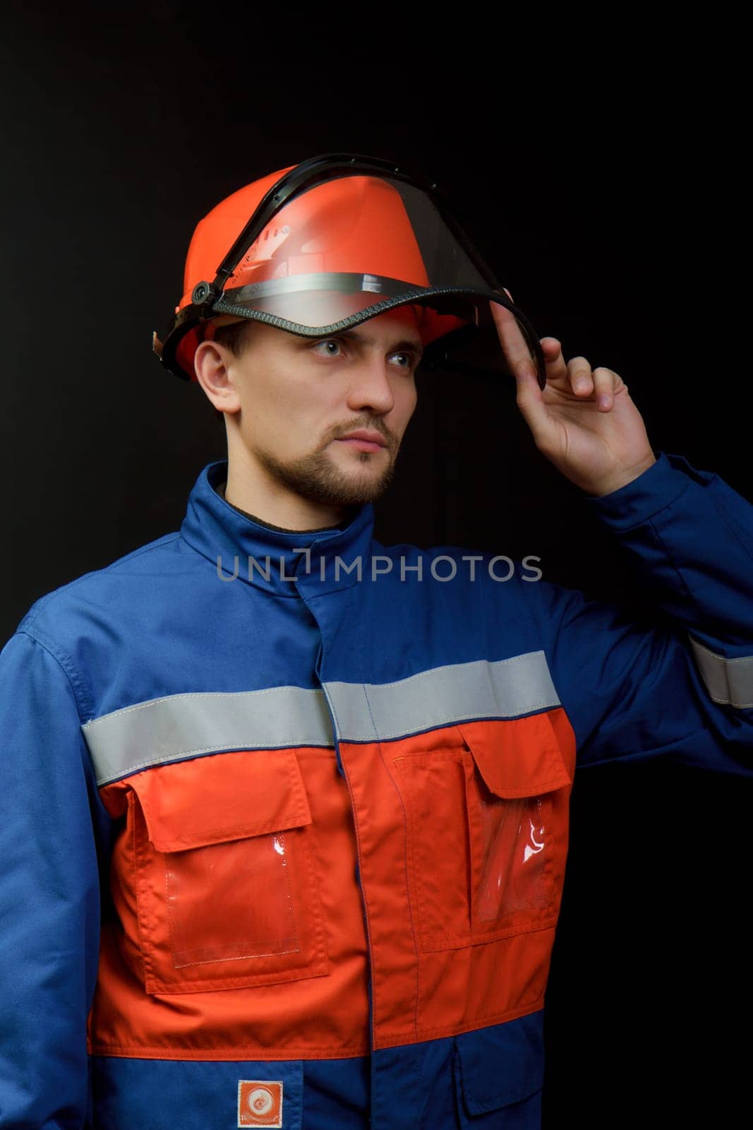 The worker in overalls and a helmet on a black background