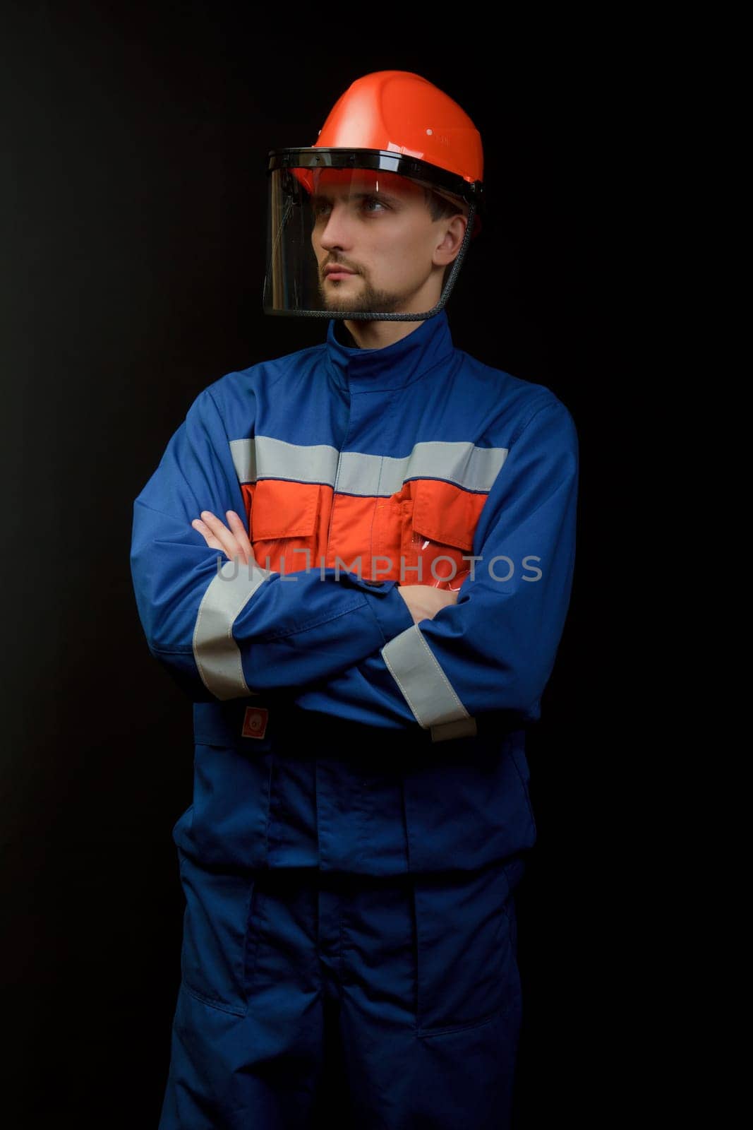 The worker in overalls and a helmet on a black background