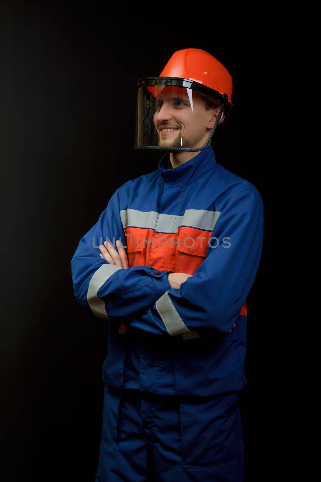 The worker in overalls and a helmet on a black background