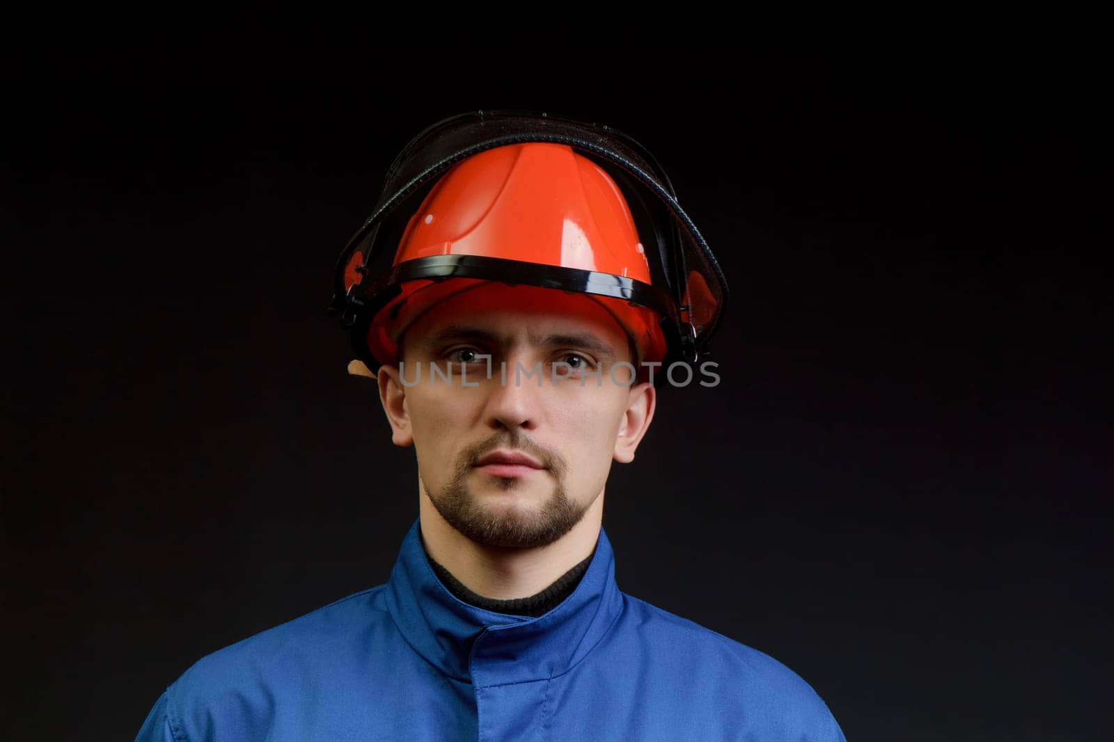 The worker in overalls and a helmet on a black background