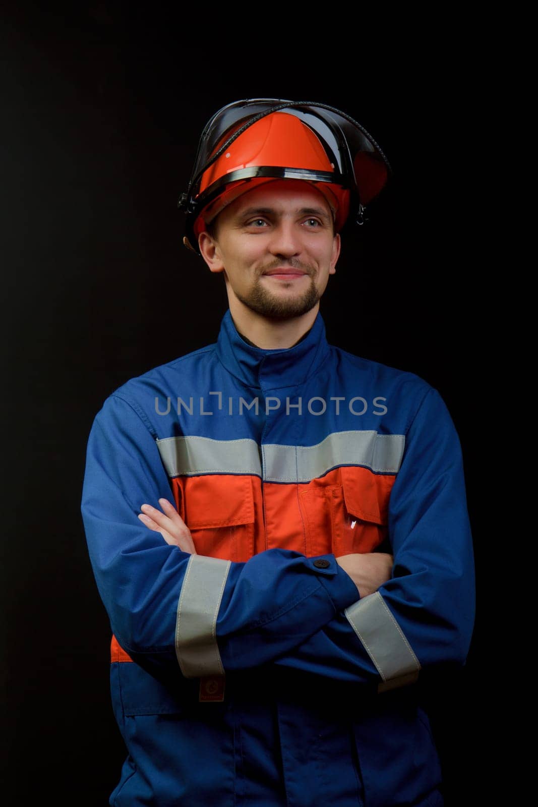 The worker in overalls and a helmet on a black background