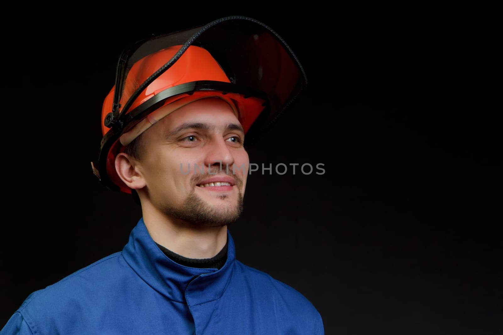 The worker in overalls and a helmet on a black background