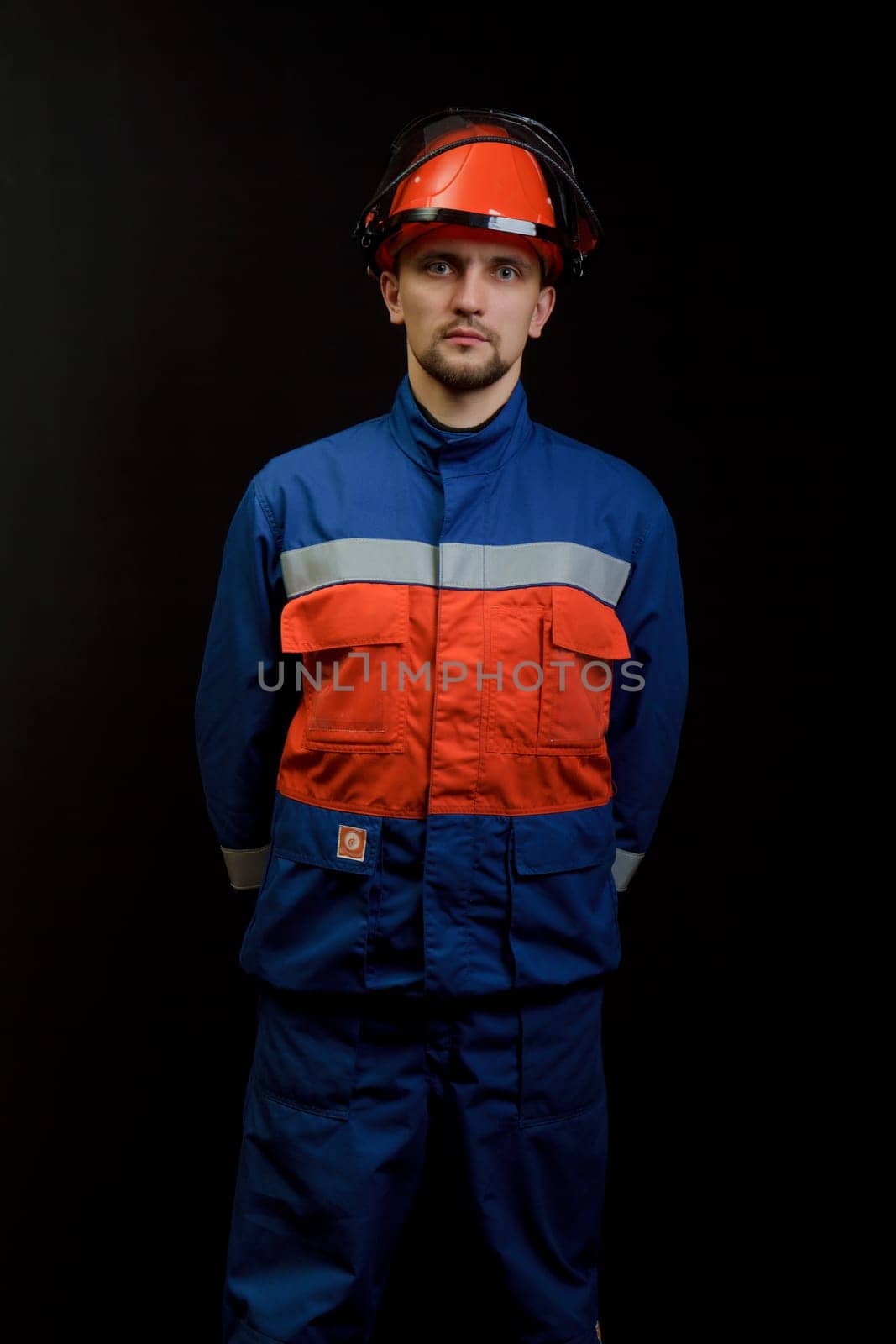 The worker in overalls and a helmet on a black background