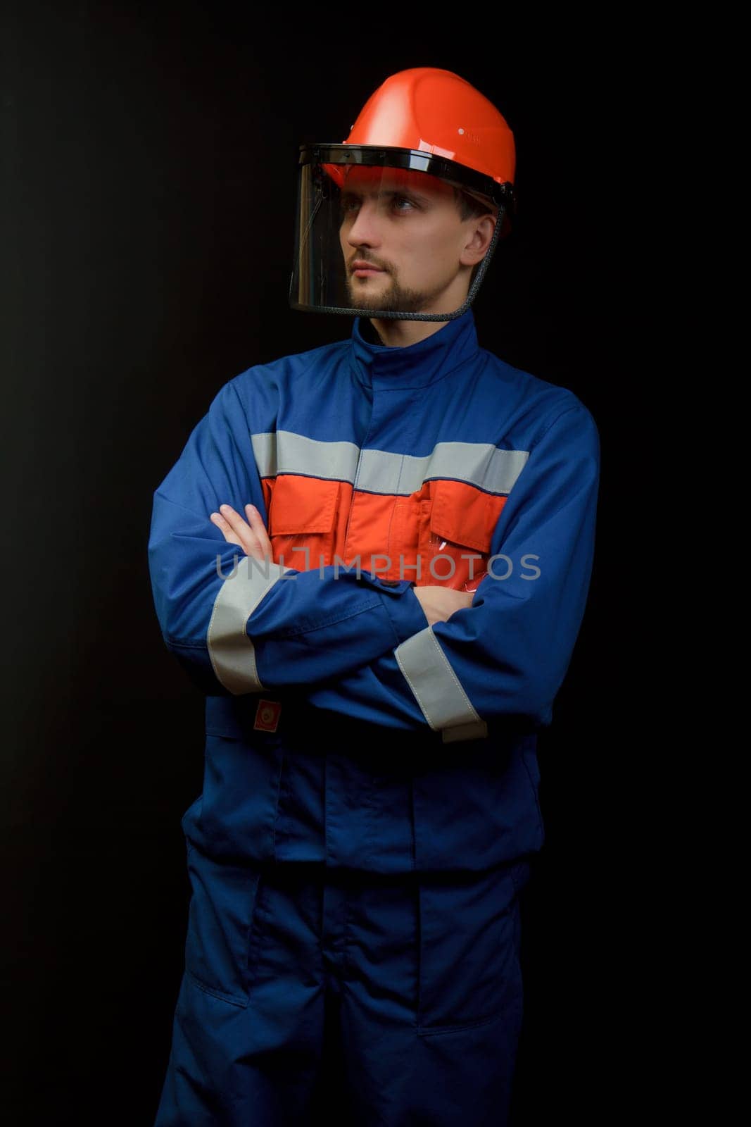 The worker in overalls and a helmet on a black background