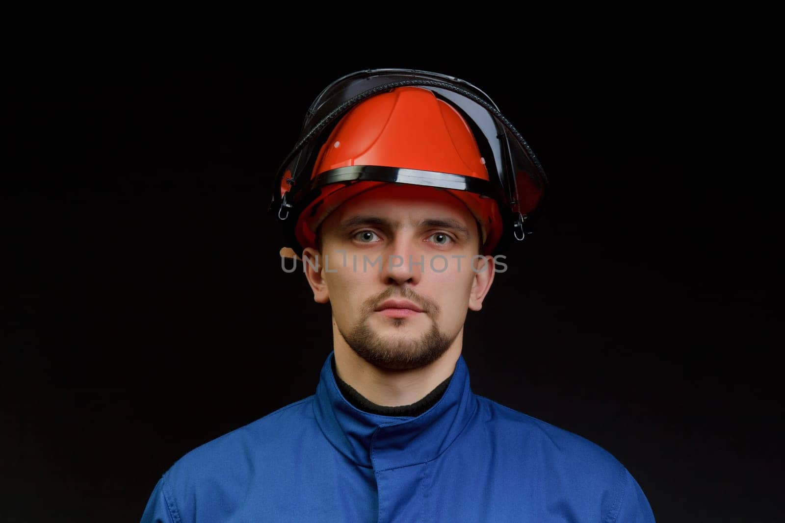 The worker in overalls and a helmet on a black background