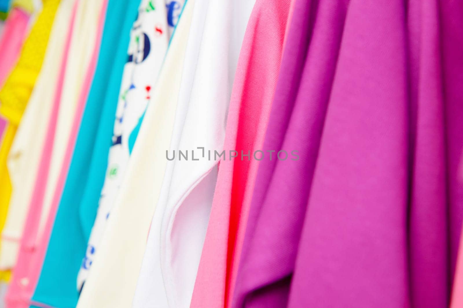a lot of bright children's clothing on a hanger in the store