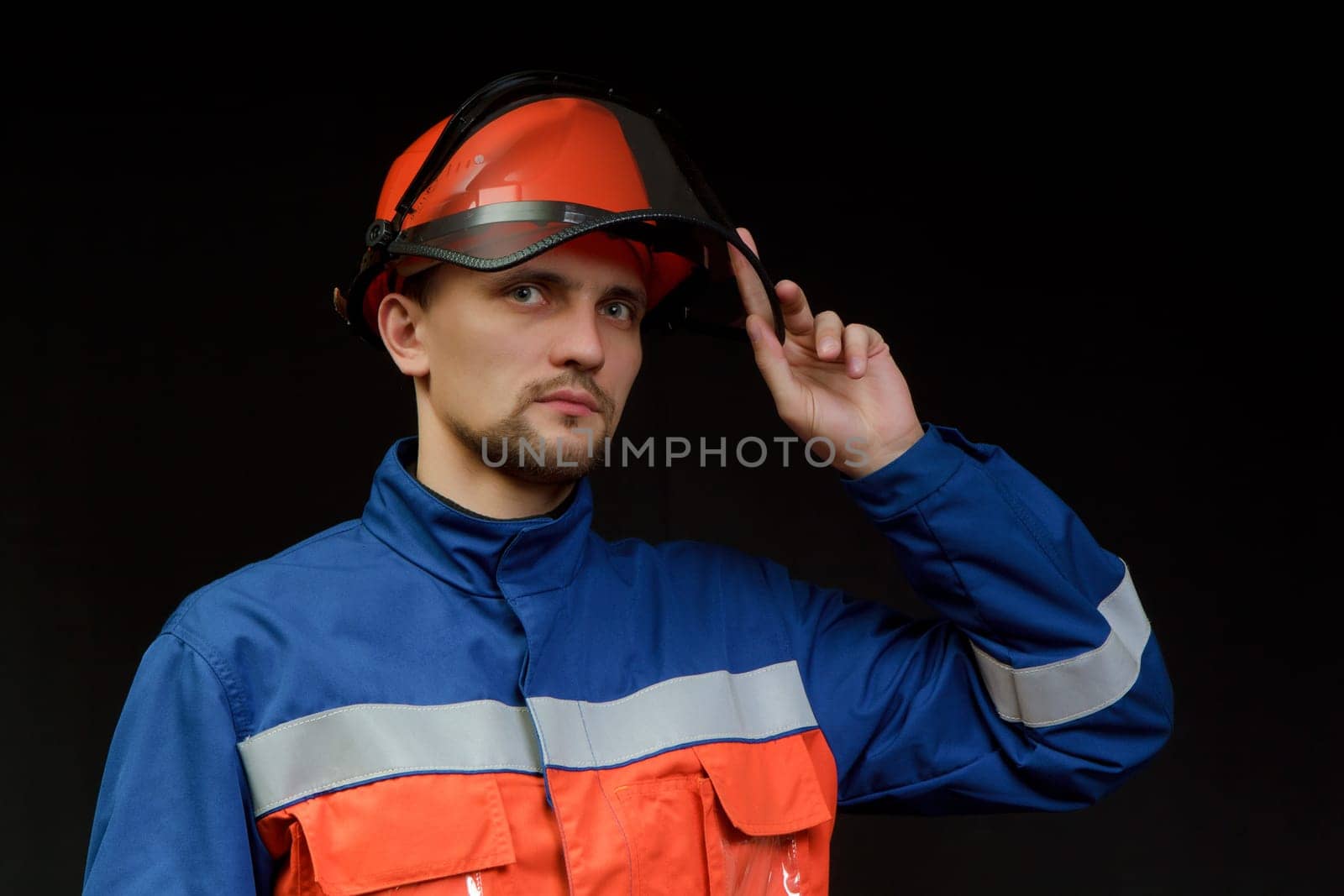 The worker in overalls and a helmet on a black background