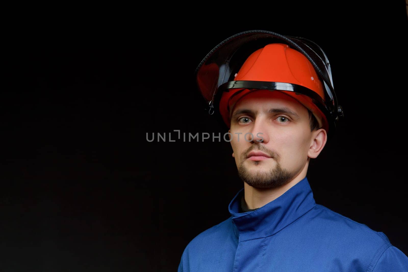 The worker in overalls and a helmet on a black background