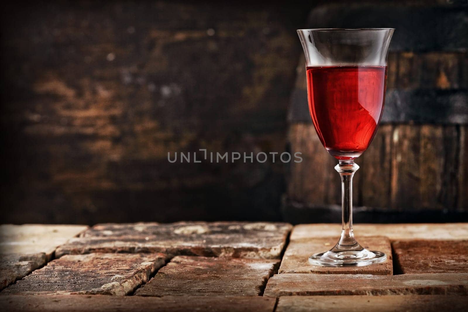 A glass of red wine on an old rustic table, shallow depth of field.