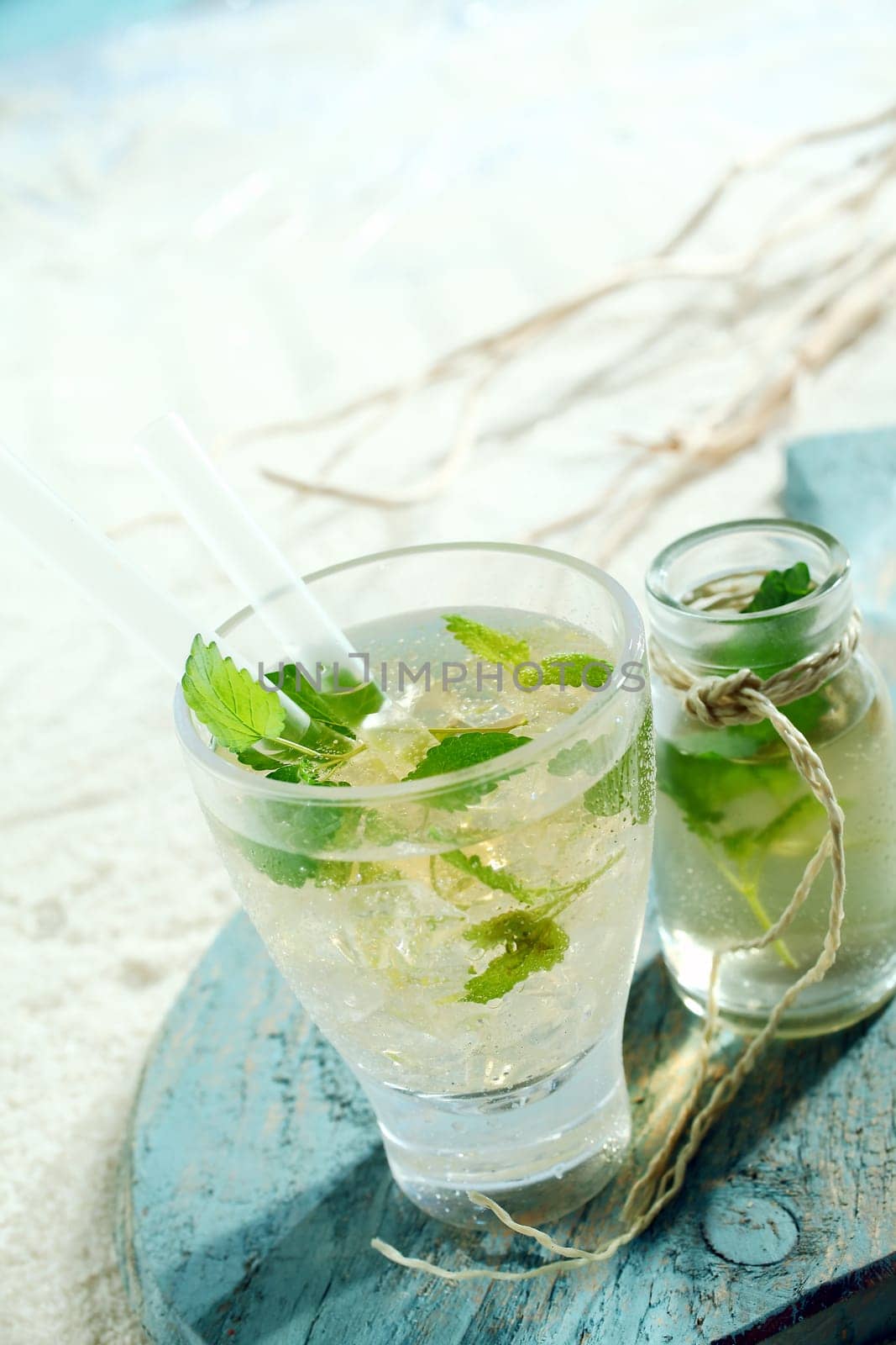 Ice cold mojito cocktail with tangy lime and mint served in a glass with an accompanying carafe