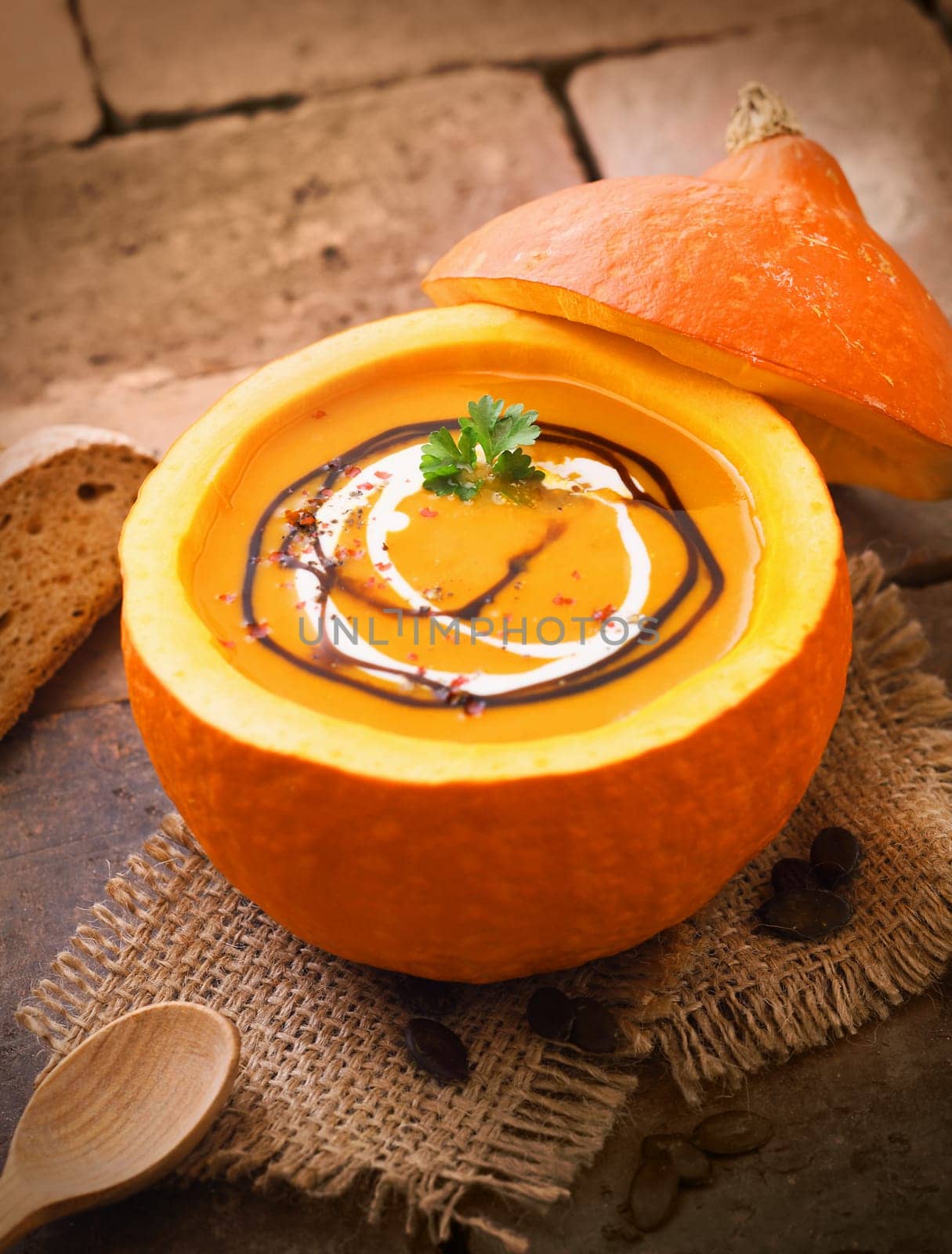 Delicious pumpkin or butternut soup served in the hollowed out gourd drizzled with cream and sauce for a hearty autumn meal