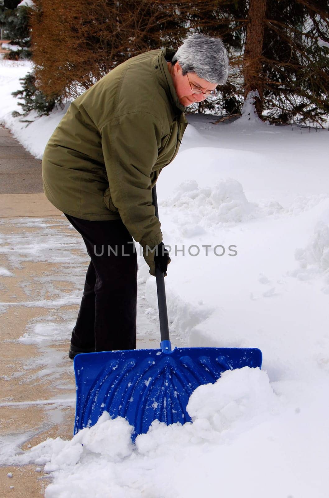 middle aged woman shoveling snow off sidewalk