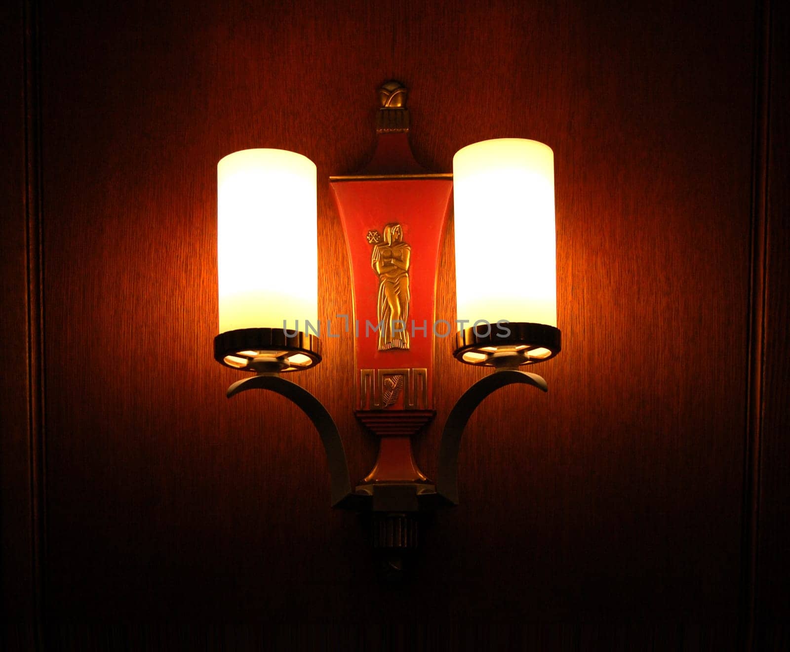Vintage wall sconce in darkened room, with sculpture