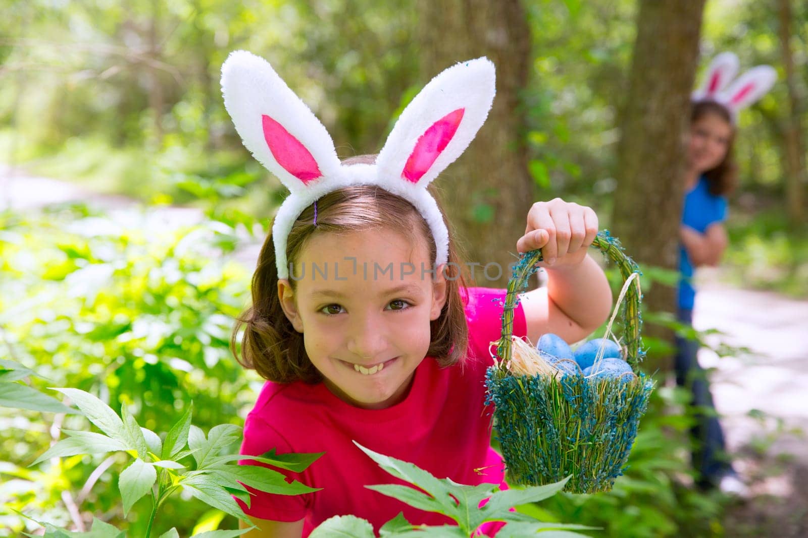 Easter girl with eggs basket and funny bunny face expression at the forest