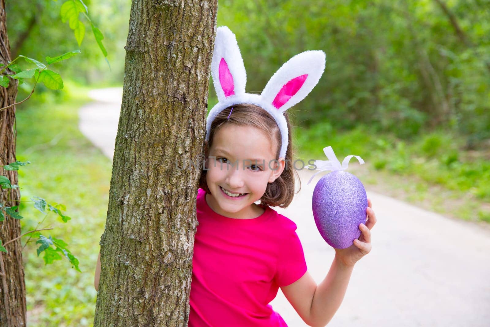 Easter girl with big purple egg and funny bunny ears on the forest