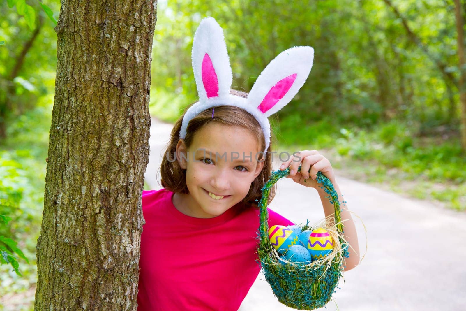 Easter girl with eggs basket and funny bunny face expression at the forest
