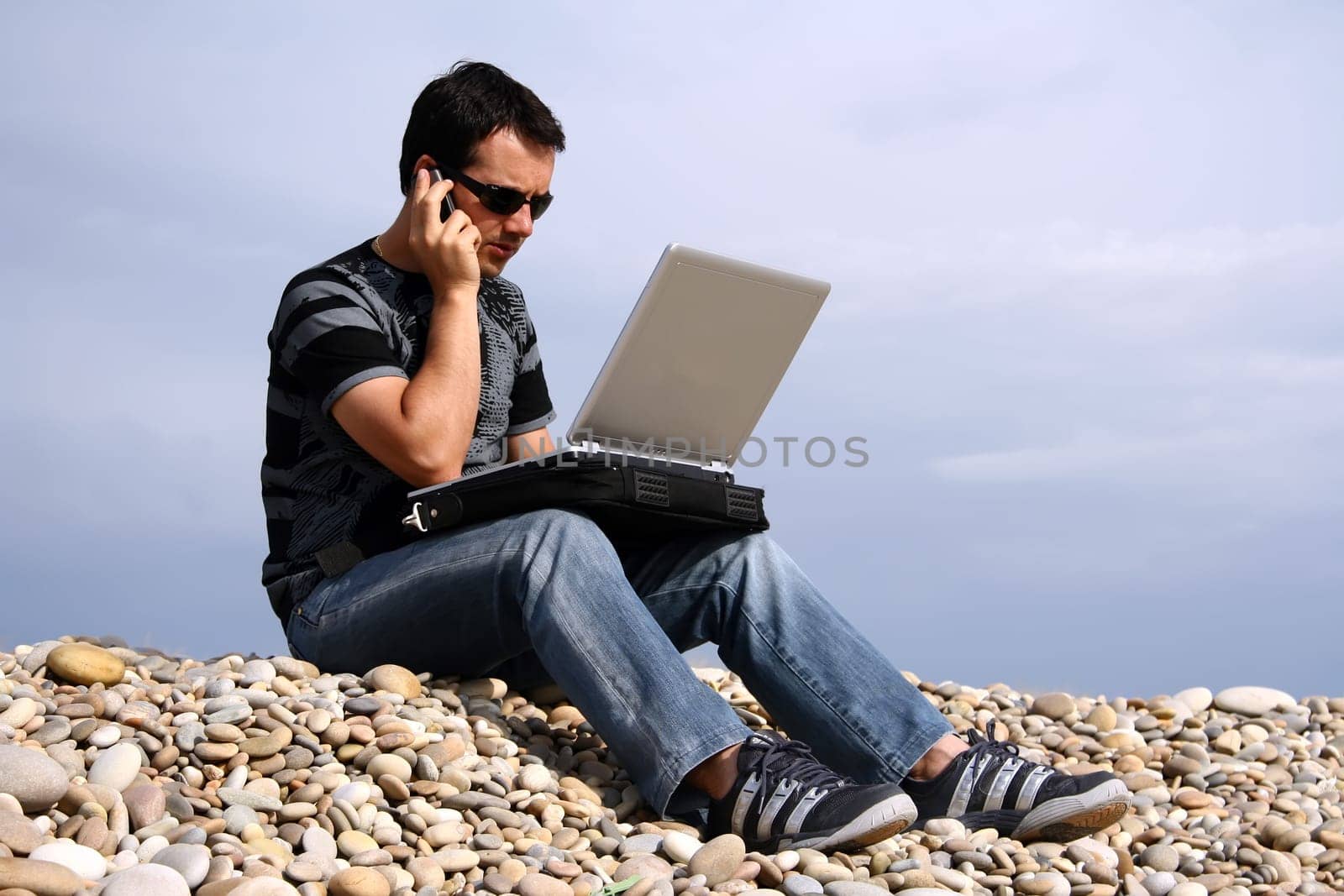 young man working on his laptop on the beach