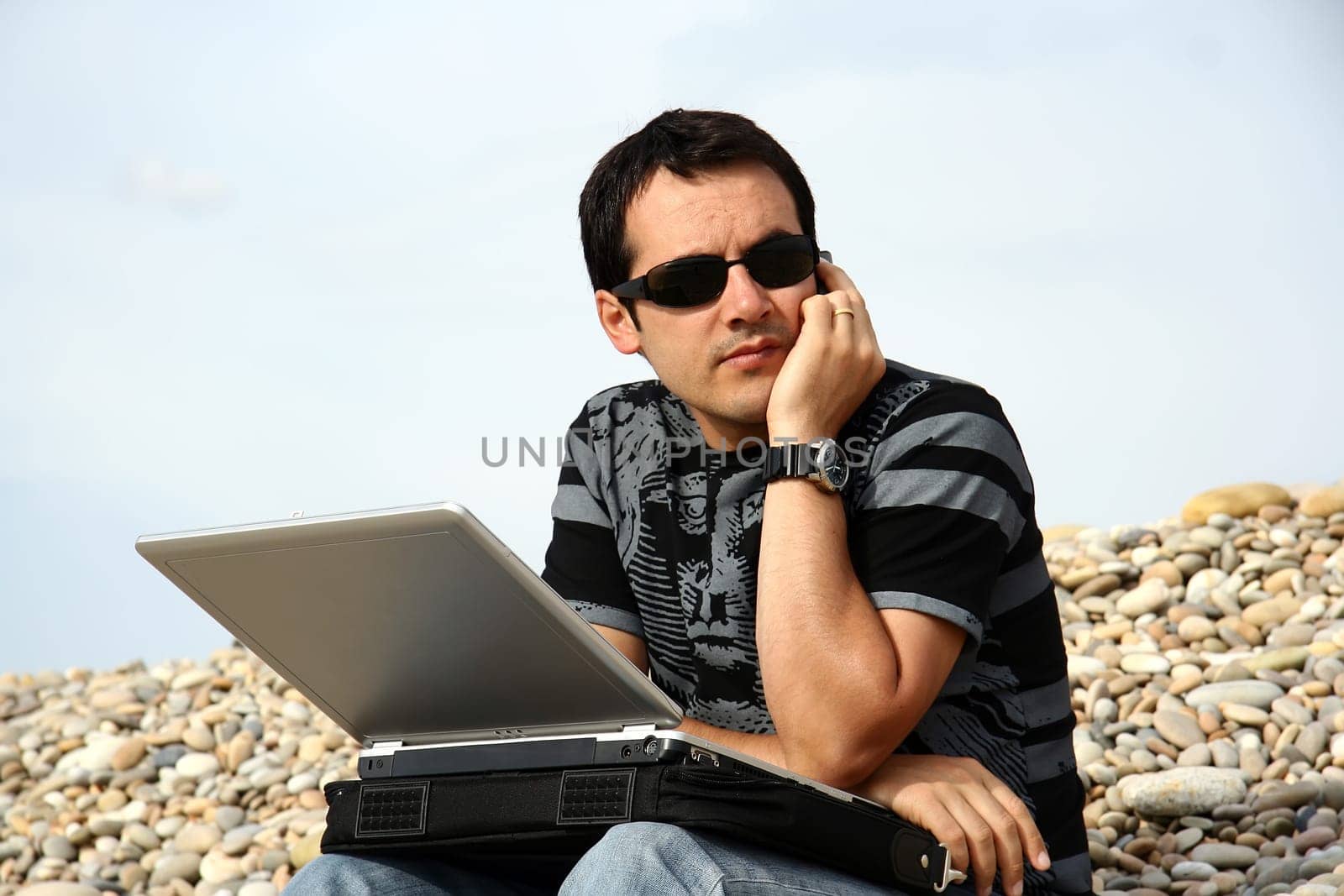 young man working on his laptop on the beach